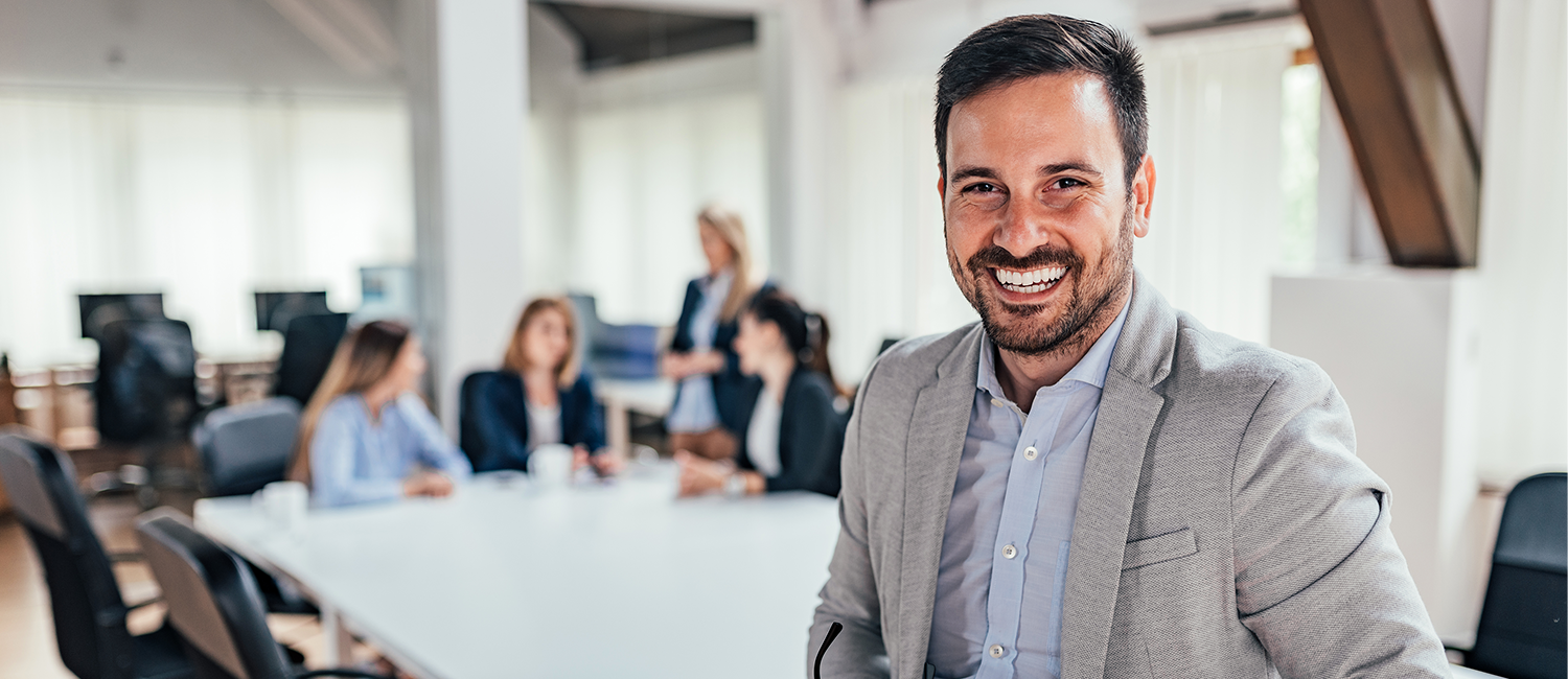Smiling business man with group of team members behind him on Instant Payments page